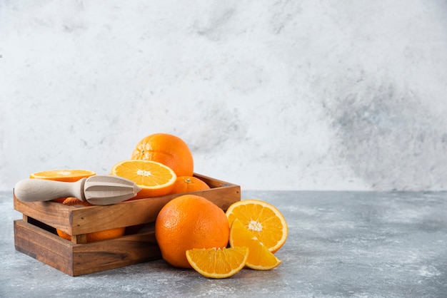 Una vieja caja de madera llena de jugosas frutas de naranja en la mesa de piedra.