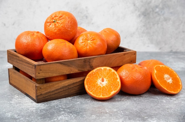 Una vieja caja de madera llena de jugosas frutas de naranja en la mesa de piedra.