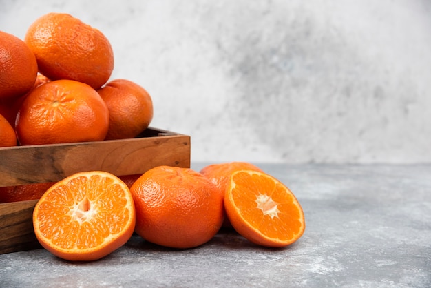 Una vieja caja de madera llena de jugosas frutas de naranja en la mesa de piedra.
