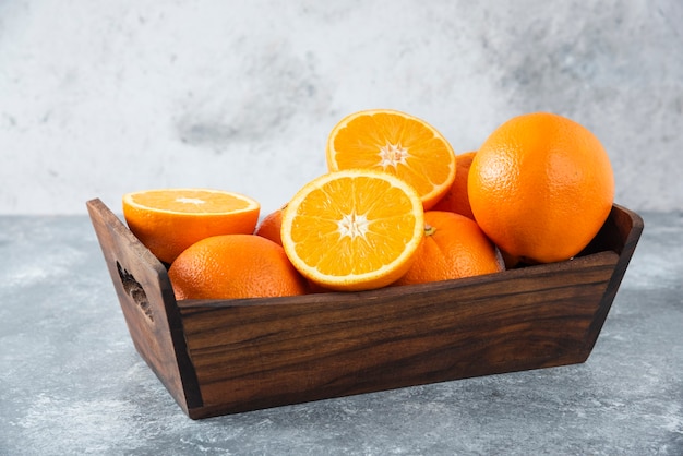 Una vieja caja de madera llena de jugosas frutas naranjas en rodajas y enteras.