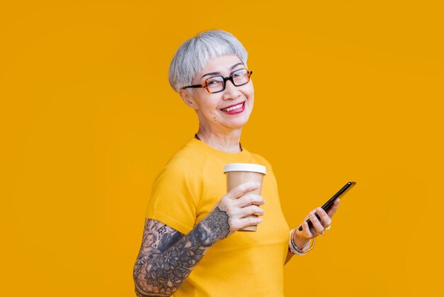 Vieja mujer asiática tatuada usando un teléfono inteligente decir hola saludo conversación videollamada a su amiga conversación casual mujer mayor de asia usando un dispositivo de teléfono inteligente tecnología de aplicación de fácil conexión