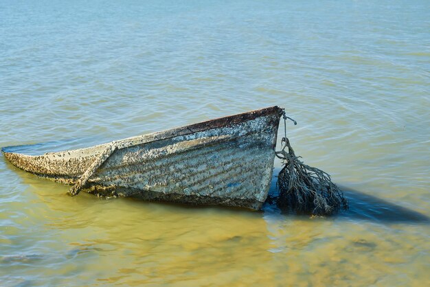 Viejo barco abandonado hundido cerca de la orilla barco hundido o abandonado cerca del mar Contaminación del agua problemas ambientales y contaminación de basura