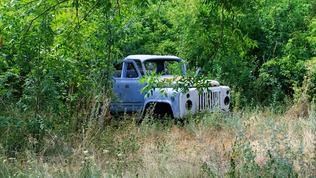 Viejo camión azul abandonado con puertas abiertas en el bosque