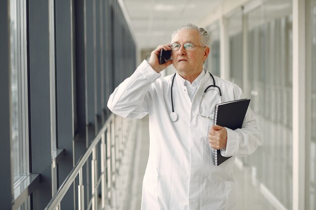 Viejo doctor en uniforme de pie en el pasillo