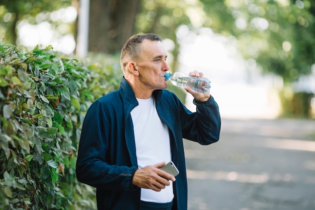 Viejo hombre agua potable en el parque