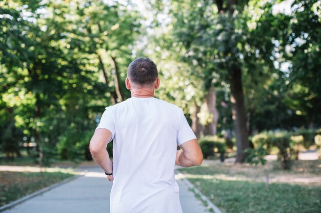 Viejo hombre en camiseta blanca corriendo en un parque