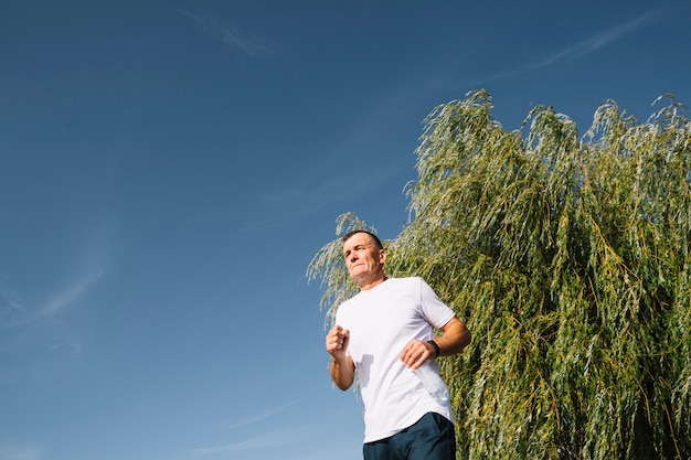 Foto gratuita viejo hombre corriendo al aire libre vista de ángulo bajo