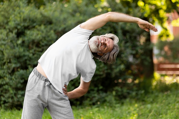 Viejo hombre estirando en la naturaleza