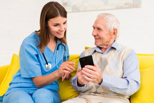 Viejo hombre mostrando fotos en el teléfono a la enfermera