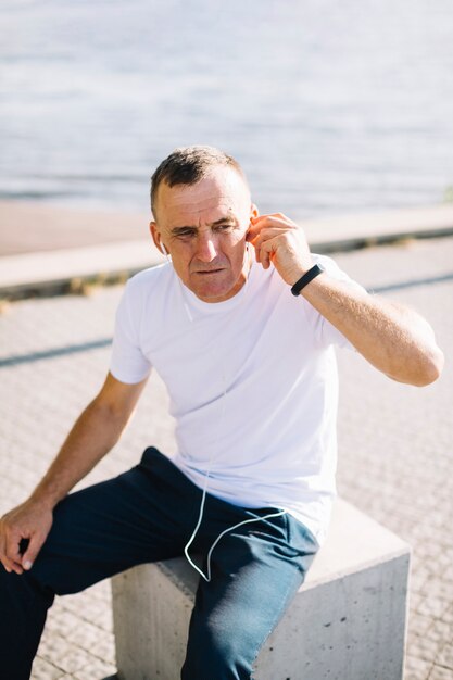 Viejo poniendo sus auriculares en sus oídos