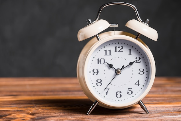 Foto gratuita un viejo reloj de alarma de la vendimia en el escritorio de madera contra el fondo negro