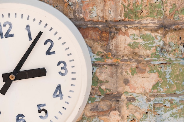 Un viejo reloj blanco contra la pared desgastada.