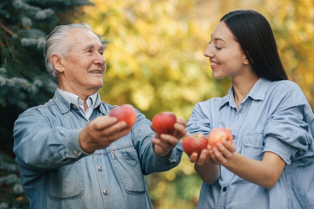 Viejo senior de pie en un jardín de verano con manzanas