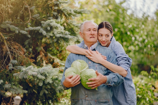 Viejo senior de pie en un jardín de verano con repollo