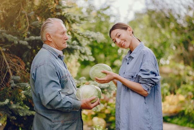 Viejo senior de pie en un jardín de verano con repollo