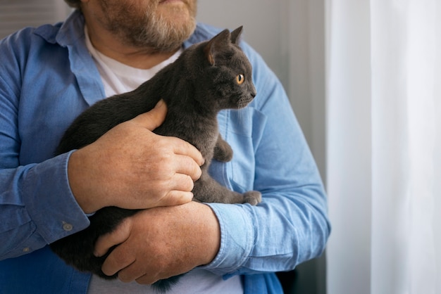 Viejo sosteniendo gato vista frontal