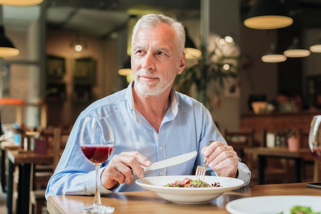 Viejo tiro medio que tiene una comida en el restaurante