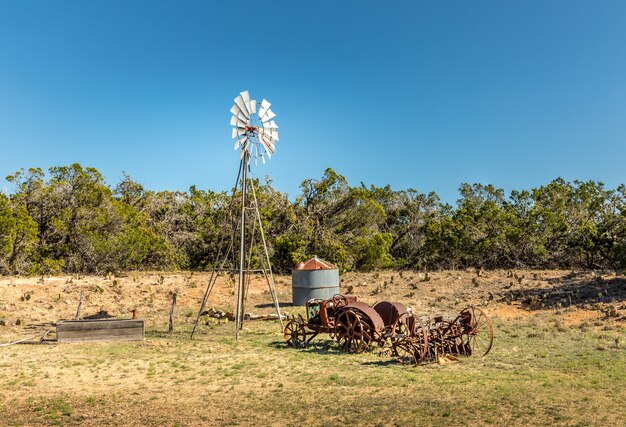 Viejo tractor oxidado y un molino de viento en las carreteras secundarias de Texas