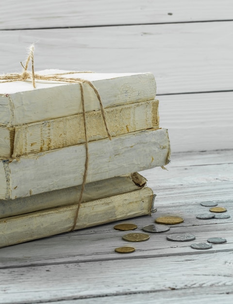 Viejos libros blancos con dinero y monedas en la pared de madera