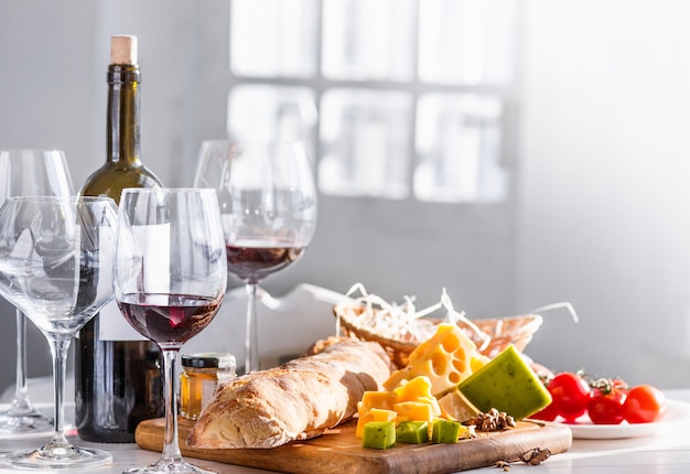 Vino, baguette y queso en mesa de madera