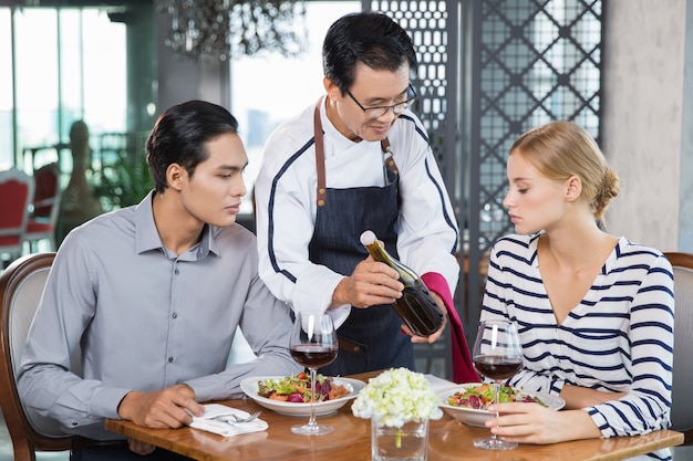 Vino tinto asiática Camarero ofrecimiento a los pares jovenes