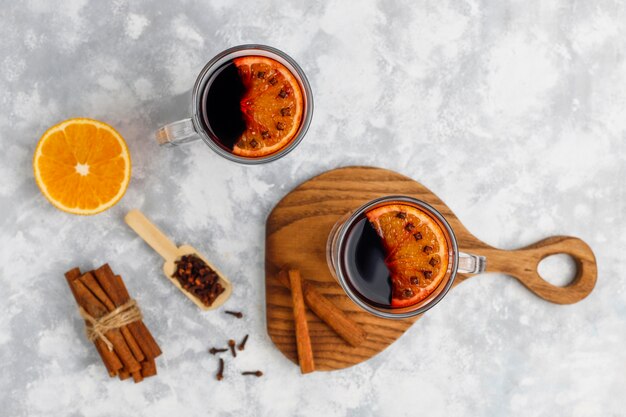 Vino tinto glintwine servido en vasos para la mesa de navidad con naranja y especias