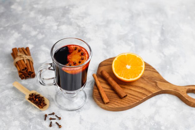 Vino tinto glintwine servido en vasos para la mesa de navidad con naranja y especias