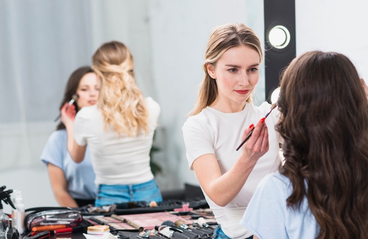 Foto gratuito visagiste creando maquillaje profesional mujer en estudio.