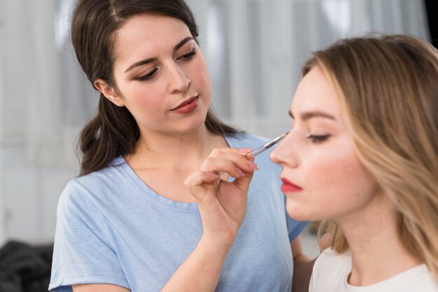 Visagiste haciendo maquillaje de ojos para cliente.