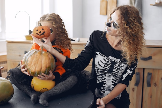 Víspera de Todos los Santos. Madre e hija en disfraz de halloween de estilo mexicano. Familia en casa con calabazas.