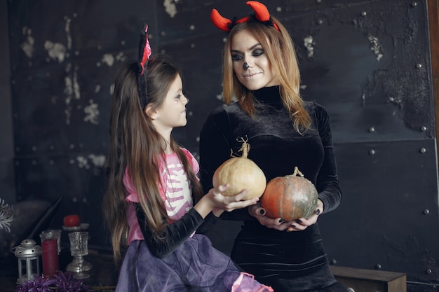 Víspera de Todos los Santos. Madre e hija disfrazadas de halloween. Familia en casa.