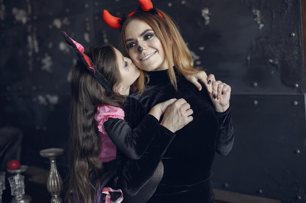 Víspera de Todos los Santos. Madre e hija disfrazadas de halloween. Familia en casa.