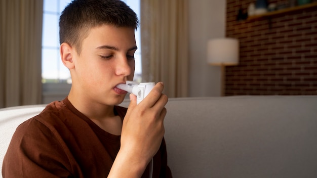 Foto gratuita vista de un adolescente que usa un inhalador en casa por problemas de salud respiratoria