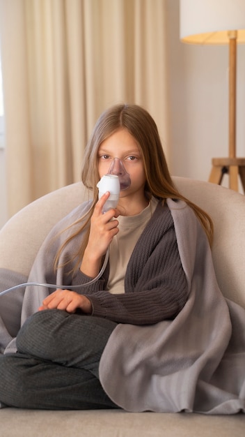 Foto gratuita vista de una adolescente que usa nebulizador en casa por problemas de salud respiratoria