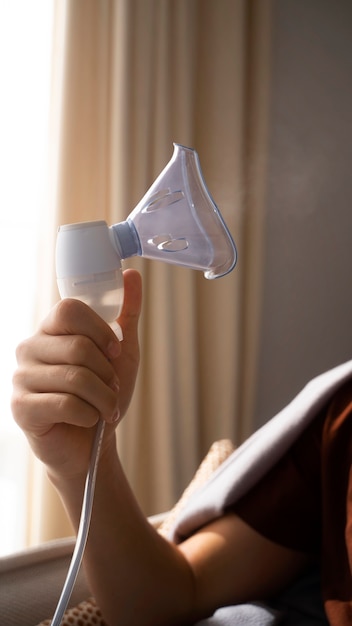 Vista de un adolescente que usa nebulizador en casa por problemas de salud respiratoria