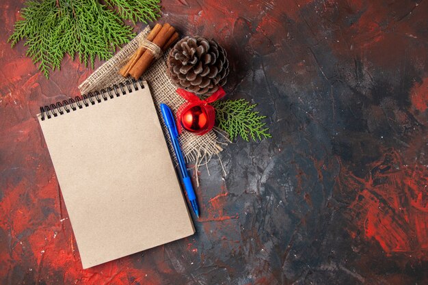 Vista aérea de accesorios de decoración conífera cono ramas de abeto canela limas y cuaderno sobre fondo oscuro