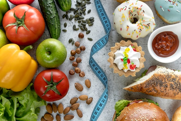 Foto gratuita vista aérea de alimentos saludables y no saludables con cinta métrica sobre fondo