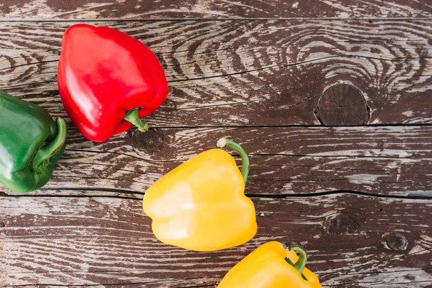 Una vista aérea de amarillo; Pimientos verdes y rojos en superficie de textura de madera