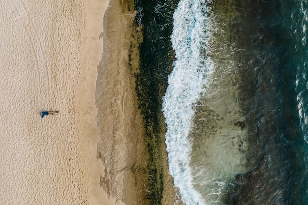 Vista aérea de arena que se encuentra con el agua de mar y las olas