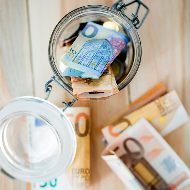 Una vista aérea de los billetes en euros en un frasco de vidrio abierto