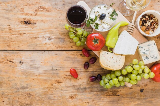 Una vista aérea de bloques de queso con uvas; los tomates ají verde y frutos secos