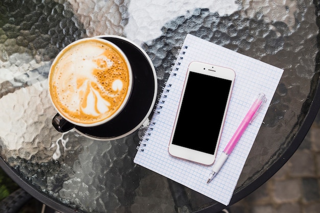 Foto gratuita vista aérea de café con teléfono móvil en cuaderno y pluma a cuadros