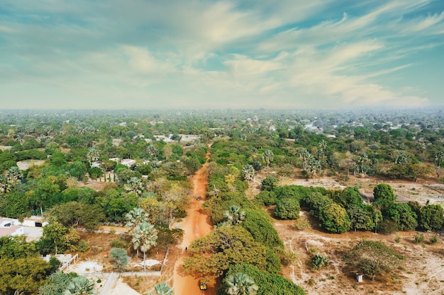 Vista aérea de un camino de tierra recto desde un pueblo con árboles alrededor