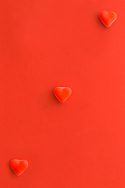 Vista aérea de caramelos de forma de corazón en superficie roja