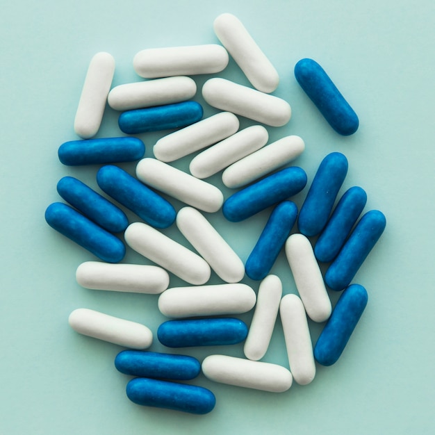 Vista aérea de caramelos ovales azules y blancos sobre fondo de color