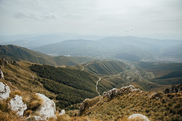 Vista aérea de una carretera rural pasando por los árboles y las montañas