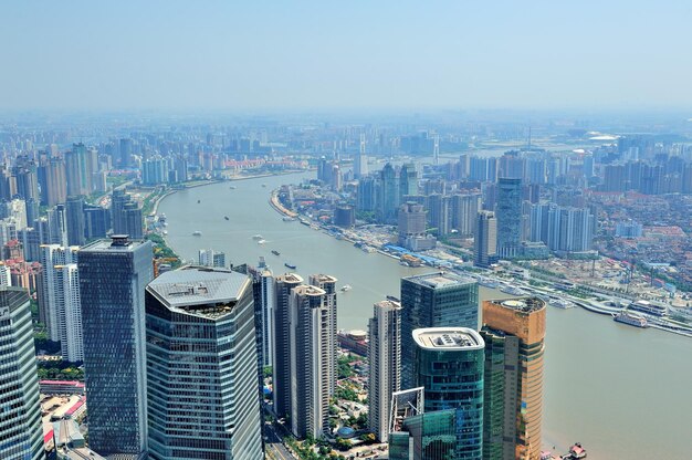 Vista aérea de la ciudad de Shanghai con arquitectura urbana sobre el río y el cielo azul en el día.