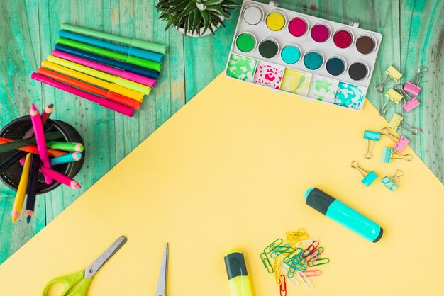 Vista aérea de un colorido suministros de artesanía y planta en maceta en mesa de madera