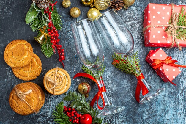 Vista aérea de copas de vidrio, accesorios de decoración, galletas apiladas, cajas de regalo sobre fondo oscuro