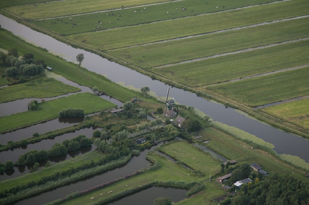 Vista aérea de una corriente de agua en medio de campos de hierba en el pólder holandés